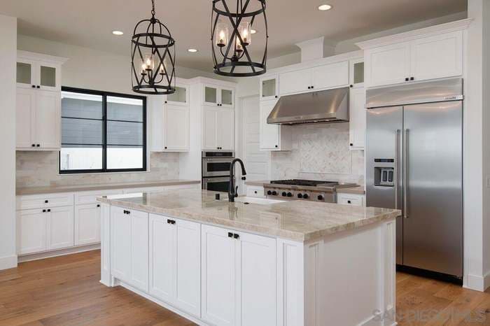 picture of a newly remodeled kitchen with white cabinets and beige granite countertops